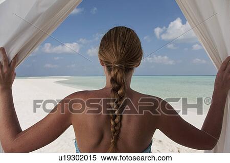 Woman admiring beach through curtains View Large Photo Image Stock Photography - Woman admiring beach through curtains. Fotosearch