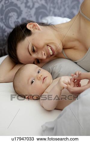 Stock Image - Woman and baby laying in bed. Fotosearch