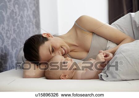 Woman and baby laying in bed View Large Photo Image Stock Photograph - Woman and baby laying in bed. Fotosearch