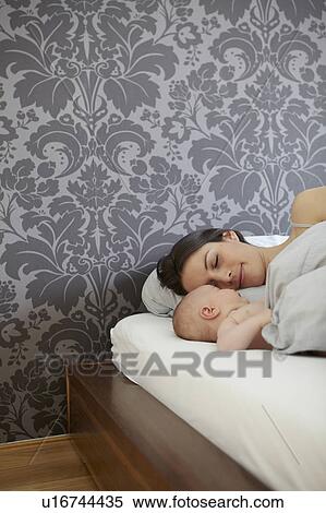 Stock Photography - Woman and baby laying in bed. Fotosearch