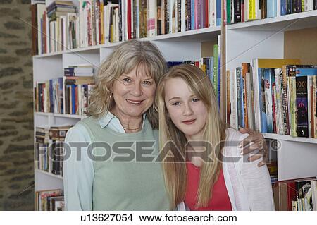 Picture - Woman and granddaughter by bookshelves. Fotosearch