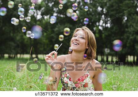 Woman blowing bubbles in field View Large Photo Image Stock Image - Woman blowing bubbles in field. Fotosearch