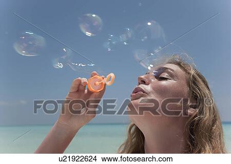 Woman blowing bubbles on beach View Large Photo Image Picture - Woman blowing bubbles on beach. Fotosearch