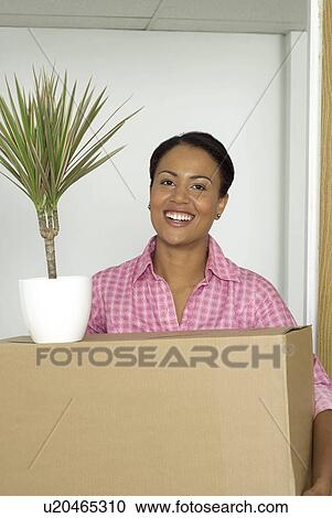 Woman carrying box and potted plant View Large Photo Image Stock Image - Woman carrying box and potted plant. Fotosearch
