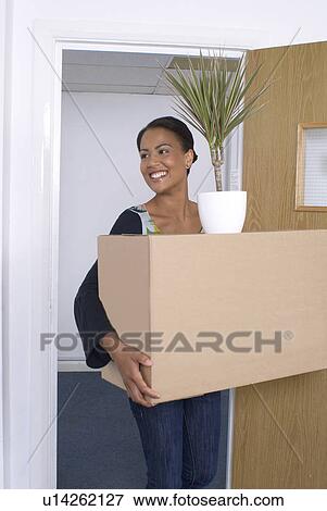 Stock Photo - Woman carrying box and potted plant. Fotosearch