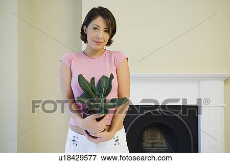 Woman carrying plant in new home View Large Photo Image Stock Photo - Woman carrying plant in new home. Fotosearch