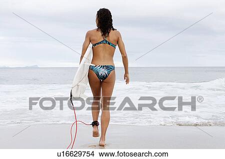 Woman carrying surfboard on beach View Large Photo Image Picture - Woman carrying surfboard on beach. Fotosearch