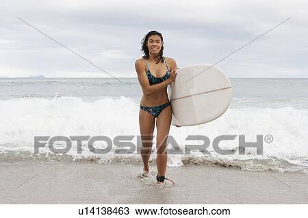 Woman carrying surfboard on beach View Large Photo Image Stock Image - Woman carrying surfboard on beach. Fotosearch