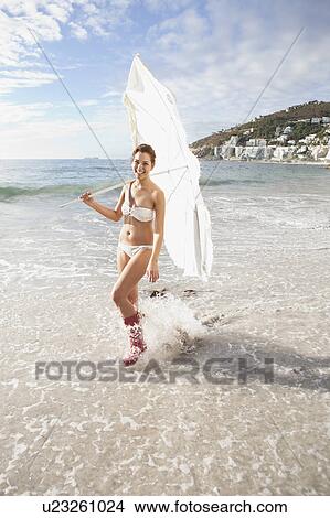 Woman carrying umbrella on beach View Large Photo Image Picture - Woman carrying umbrella on beach. Fotosearch