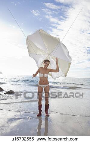Stock Photography - Woman carrying umbrella on beach. Fotosearch