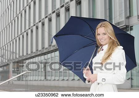 Woman carrying umbrella on city street View Large Photo Image Stock Image - Woman carrying umbrella on city street. Fotosearch