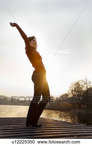 Woman cheering on jetty over lake View Large Photo Image Stock Image - Woman cheering on jetty over lake. Fotosearch