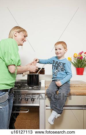 Woman cooking with son in kitchen View Large Photo Image Stock Image - Woman cooking with son in kitchen. Fotosearch