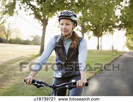 Stock Image - Woman cycling at park. Fotosearch