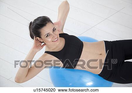Stock Image - Woman doing sit-ups on exercise ball. Fotosearch