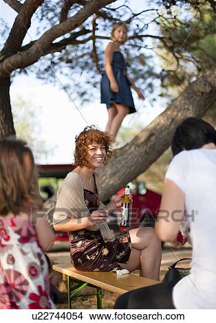 Picture - Woman drinking beer at party outdoors. Fotosearch
