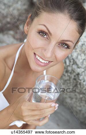 Stock Photo - Woman drinking glass of water on beach. Fotosearch