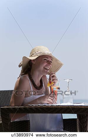 Woman drinking juice at table outdoors View Large Photo Image Picture - Woman drinking juice at table outdoors . Fotosearch