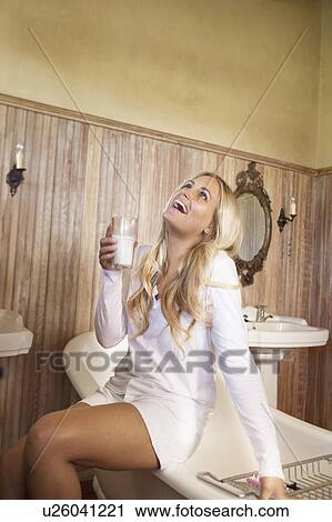 Stock Image - Woman drinking milk in bathroom. Fotosearch