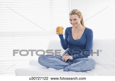 Woman drinking orange juice on couch View Large Photo Image Stock Image - Woman drinking orange juice on couch. Fotosearch