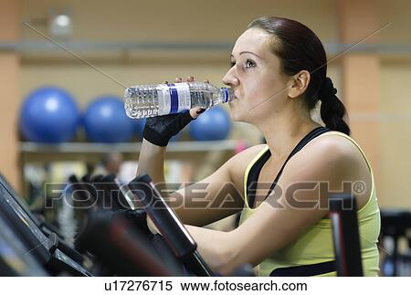 Stock Photography - Woman drinking water at gym. Fotosearch
