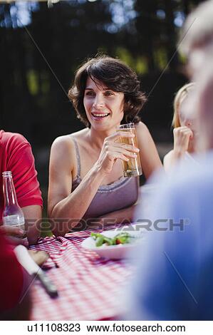 Stock Image - Woman drinking with family at picnic. Fotosearch
