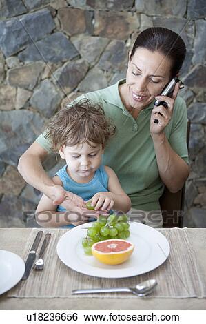 Stock Photograph - Woman eating breakfast with son. Fotosearch
