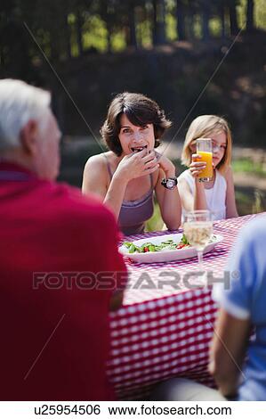 Woman eating with family at picnic table View Large Photo Image Stock Photograph - Woman eating with family at picnic table. Fotosearch