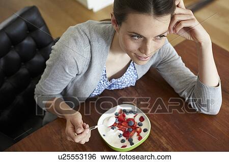 Stock Photograph - Woman eating yogurt and fruit. Fotosearch