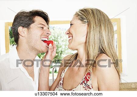 Picture - Woman feeding boyfriend strawberry. Fotosearch
