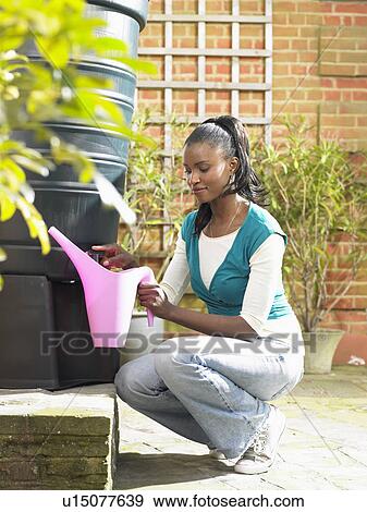 Stock Photo - Woman filling jug with recycled water. Fotosearch