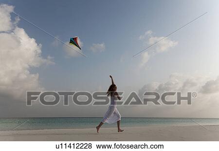 Woman flying a kite on tropical beach View Large Photo Image Stock Photo - Woman flying a kite on tropical beach. Fotosearch