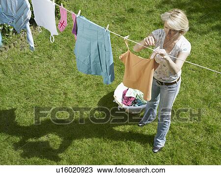 Stock Image - Woman hanging clothes on clothesline. Fotosearch