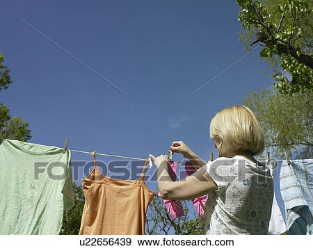 Woman hanging clothes on clothesline View Large Photo Image Stock Photo - Woman hanging clothes on clothesline. Fotosearch