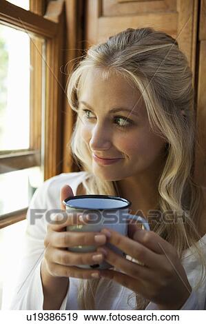Stock Photo - Woman having cup of coffee by window. Fotosearch