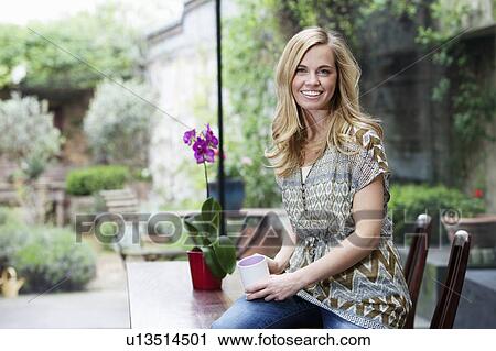 Stock Image - Woman having cup of coffee in kitchen. Fotosearch