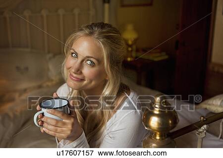 Woman having cup of coffee on bed View Large Photo Image Stock Photo - Woman having cup of coffee on bed. Fotosearch