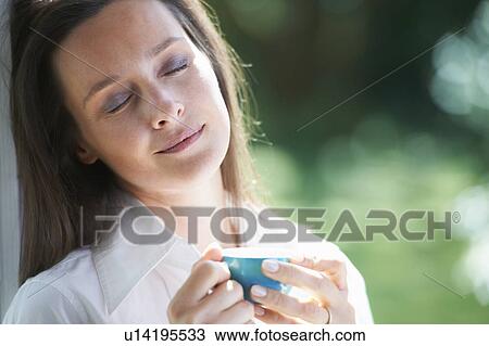Stock Image - Woman having cup of coffee outdoors. Fotosearch
