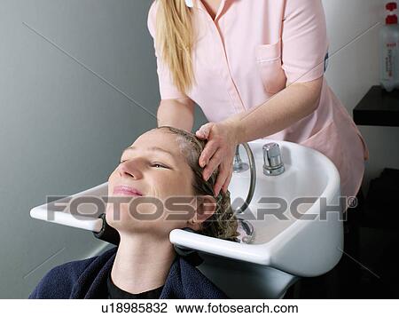 Stock Image - Woman having her hair washed in salon. Fotosearch