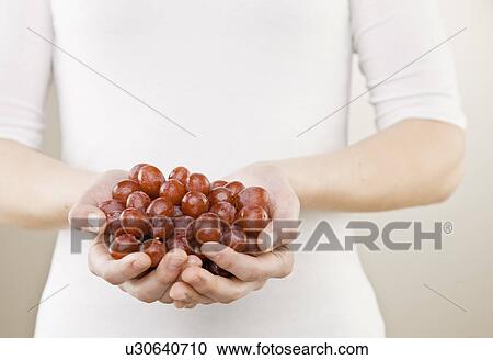 Stock Image - Woman holding bunch of grapes. Fotosearch