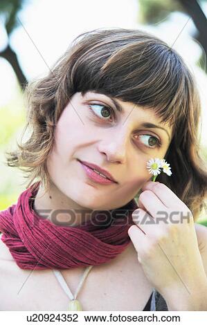 Stock Image - Woman holding daisies outdoors. Fotosearch
