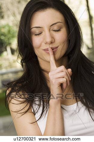 Woman holding finger to her lips View Large Photo Image Stock Image - Woman holding finger to her lips. Fotosearch