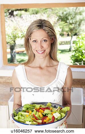 Woman holding salad in kitchen View Large Photo Image Stock Photo - Woman holding salad in kitchen. Fotosearch