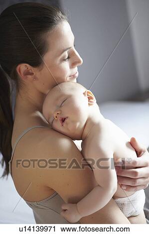 Stock Image - Woman holding sleeping baby. Fotosearch