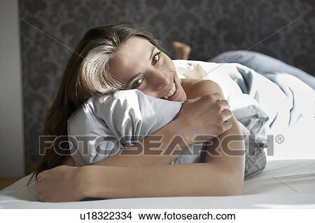 Woman hugging pillow in bed View Large Photo Image Picture - Woman hugging pillow in bed. Fotosearch