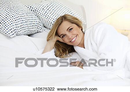 Woman in bathrobe laying on bed View Large Photo Image Stock Image - Woman in bathrobe laying on bed. Fotosearch