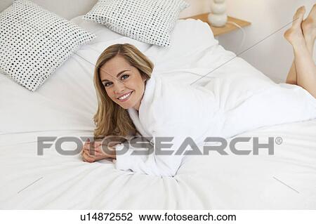 Woman in bathrobe laying on bed View Large Photo Image Stock Image - Woman in bathrobe laying on bed. Fotosearch