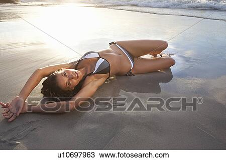 Woman in bikini laying on beach View Large Photo Image Stock Image - Woman in bikini laying on beach. Fotosearch