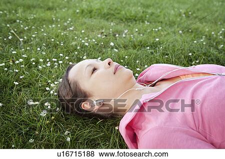 Woman in headphones laying in grass View Large Photo Image Stock Photo - Woman in headphones laying in grass. Fotosearch