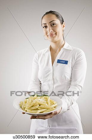 Woman in nametag holding plate of pasta View Large Photo Image Stock Photo - Woman in nametag holding plate of pasta. Fotosearch